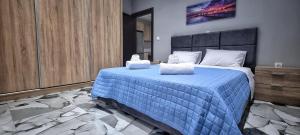 a bedroom with a blue bed with two towels on it at Mimarxos Luxury Apartments in Chalkida