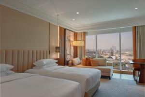 a hotel room with two beds and a couch at Grand Hyatt Dubai in Dubai
