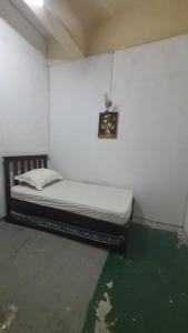 SPOT ON 90836 Penginapan Almera في إنانام: سرير في غرفة بجدار أبيض