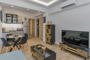 a living room with a large television and a kitchen at Pap's Lab Apartments in Heraklio