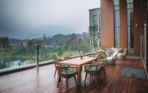 einen Holztisch und Stühle auf einem Balkon mit einem großen Fenster in der Unterkunft Le Méridien Emei Mountain Resort in Emeishan