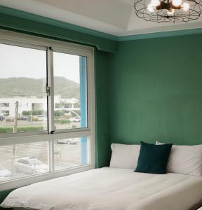 墾丁的住宿－海中天旅店 Sea Of The World B&B，一间卧室设有绿色的墙壁和一张带窗户的床