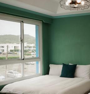 a bedroom with a green wall and a bed with a window at 海中天旅店 Sea Of The World B&B in Kenting