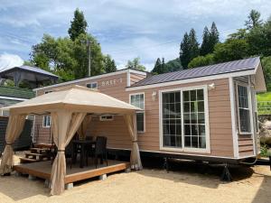 una casa pequeña con una mesa y una sombrilla en ぽかぽかランド美麻 en Omachi