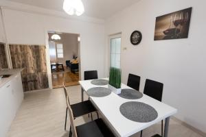 Il comprend une cuisine et une salle à manger avec une table et des chaises blanches. dans l'établissement Casuta cu View, à Sighişoara