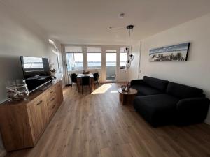 een woonkamer met een zwarte bank en een tafel bij Ferienwohnung Havenwelten in Bremerhaven