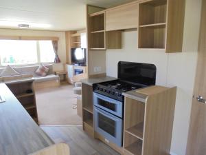 a small kitchen with a stove and a living room at Kingfisher : Horizon II:- 8 Berth, Close to site entrance in Ingoldmells