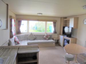 a living room with a couch and a tv at Kingfisher : Horizon II:- 8 Berth, Close to site entrance in Ingoldmells