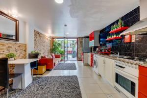 a kitchen with red cabinets and a living room at Garden in Town Hostel in Porto