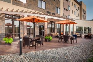 een patio met tafels, stoelen en parasols bij Courtyard by Marriott Indianapolis Noblesville in Noblesville