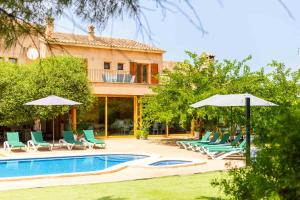 a pool with chairs and umbrellas next to a house at La Forca in Santa Margalida