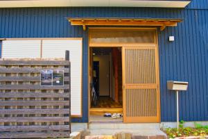 a blue building with an open door with a dog outside at root hakone in Hakone