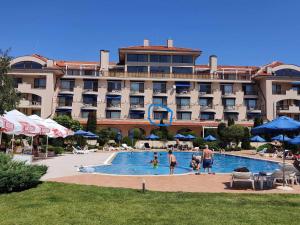 a hotel with a swimming pool in front of a building at SUN AND FLOWERS APARTMENTS in front of the sea in Topola