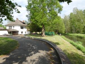 a road in front of a white house with a river at Ferienwohnung Duschka "Direkt am Fließ" in Kolonie