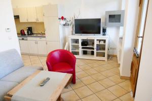 ein Wohnzimmer mit einem roten Sessel und einem Fernseher in der Unterkunft Villa Bella - direkt an der Promenade in Ahlbeck