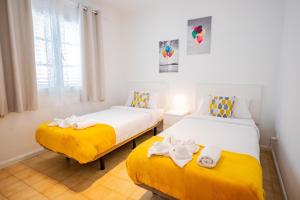two beds in a room with yellow and white at Penthouse Ocean View Puerto del Carmen in Puerto del Carmen