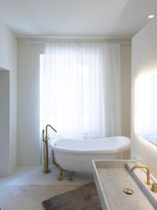 ein weißes Bad mit einer Badewanne und einem Fenster in der Unterkunft Château du Pont d'Oye in Habay-la-Neuve