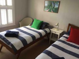 a bedroom with two beds and a table with a lamp at Pretty coastal victorian cottage in Yarmouth IOW in Yarmouth