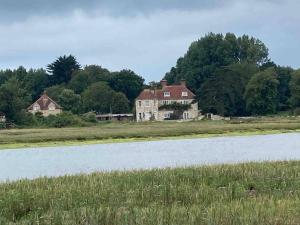 a large house in a field next to a lake at Pretty coastal victorian cottage in Yarmouth IOW in Yarmouth