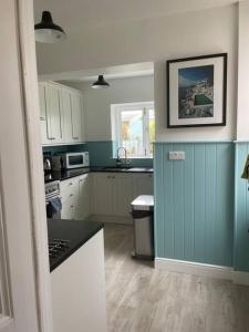a kitchen with blue walls and white cabinets at Pretty coastal victorian cottage in Yarmouth IOW in Yarmouth
