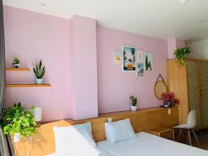 a bedroom with a white bed and a pink wall at Rustic house in Cat Ba