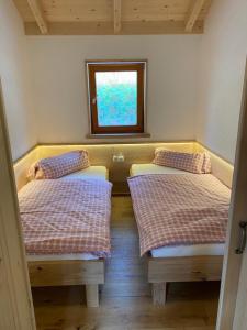 two beds in a small room with a window at Ferienhütte Sonnreith in Spital am Pyhrn