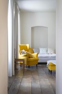 un salon avec un canapé jaune et un fauteuil jaune dans l'établissement Château du Pont d'Oye, à Habay-la-Neuve