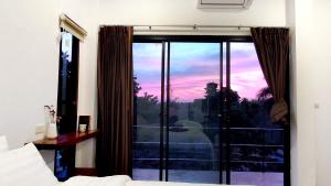 a bedroom with a window with a view of a sunset at Sam's House koh Lanta in Phra Ae beach