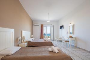 um quarto de hotel com duas camas e uma secretária em Koni Village Hotel em Stalida