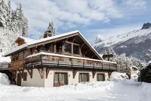 a house covered in snow with mountains in the background at Chalet Le Favre in Chamonix-Mont-Blanc