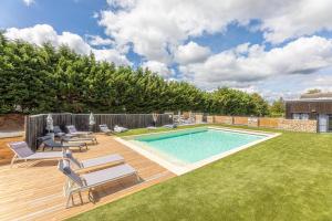 un patio trasero con piscina y terraza de madera en La Maison du Bois Brûlé 3 - Avec piscine partagée, en Villaines-les-Rochers