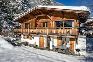 una cabaña de madera en la nieve con árboles nevados en Chalet Capricorne en Chamonix-Mont-Blanc