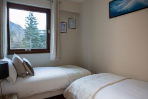 Duas camas num quarto com uma janela em Le Brevent 2 Apartment em Chamonix-Mont-Blanc