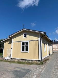 a large yellow building with two windows on a street at In the heart of Old Rauma in Rauma