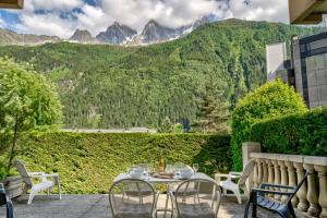 un patio con tavolo e sedie con montagne sullo sfondo di Villa Floria Apartment a Chamonix-Mont-Blanc