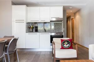 eine Küche mit weißen Schränken und einem Tisch mit roten Kissen in der Unterkunft Villa Floria Apartment in Chamonix-Mont-Blanc