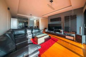 a living room with a black leather couch and a red rug at Casa da Terça Nice View and Parking in Funchal