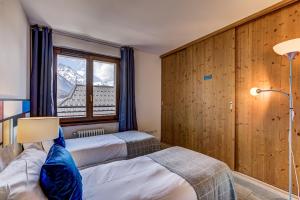 シャモニー・モンブランにあるResidence Les Alpesのベッド2台と窓が備わるホテルルームです。