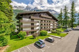 ein Apartmenthaus mit Autos auf einem Parkplatz in der Unterkunft Le Brevent 3 Apartment in Chamonix-Mont-Blanc