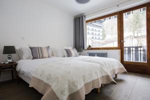 Schlafzimmer mit einem großen weißen Bett und einem Fenster in der Unterkunft Le Brevent 3 Apartment in Chamonix-Mont-Blanc