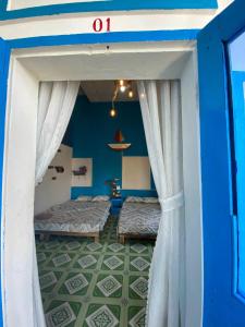 two beds in a room with blue walls and curtains at Cá Mặn Homestay in Quy Nhon