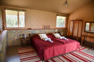 ein Schlafzimmer mit einem roten Bett mit zwei Kissen darauf in der Unterkunft Mara Siria Tented Camp & Cottages in Aitong