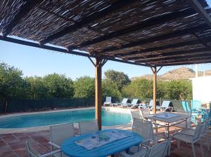un patio con mesa, sillas y piscina en Casa rural la Estrella, en Pizarra