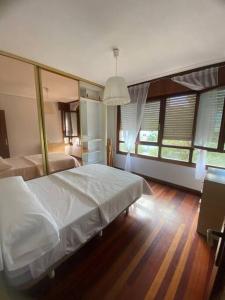 - une chambre avec un grand lit blanc et quelques fenêtres dans l'établissement Amplio y céntrico piso en Santoña, à Santoña