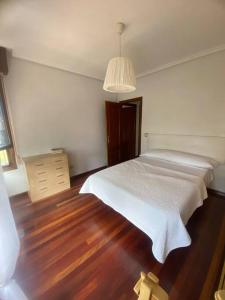 a bedroom with a white bed and a wooden floor at Amplio y céntrico piso en Santoña in Santoña
