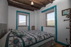 um quarto com uma cama e duas janelas em Casa da Avó Emília em Arganil