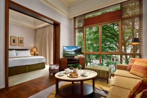 新加坡的住宿－Treetops Executive Residences，一间带一张床的房间和一间带桌子的客厅