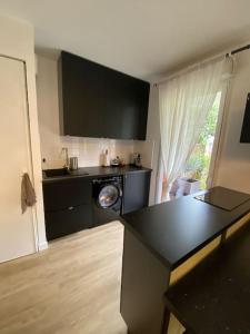 a kitchen with black cabinets and a washing machine at Le studio de Manon in Carquefou