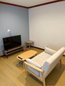 a living room with a couch and a tv at Pension Bonnard in Hakuba