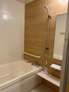 a bathroom with a tub and a sink and a mirror at Pension Bonnard in Hakuba